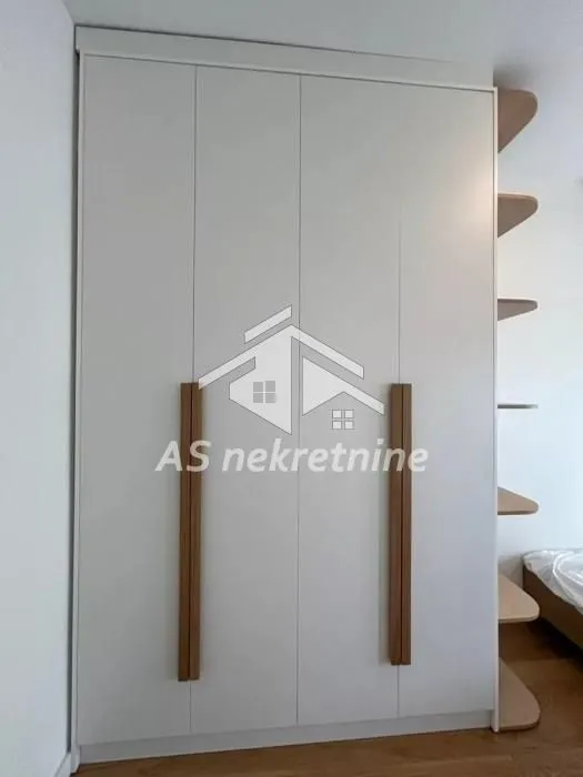 Large white wardrobe with wooden handles and side shelves in the bedroom.