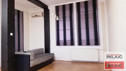 Dnevna soba sa garniturom, parketom na podu i velikim prozorima sa roletnama. - image 3