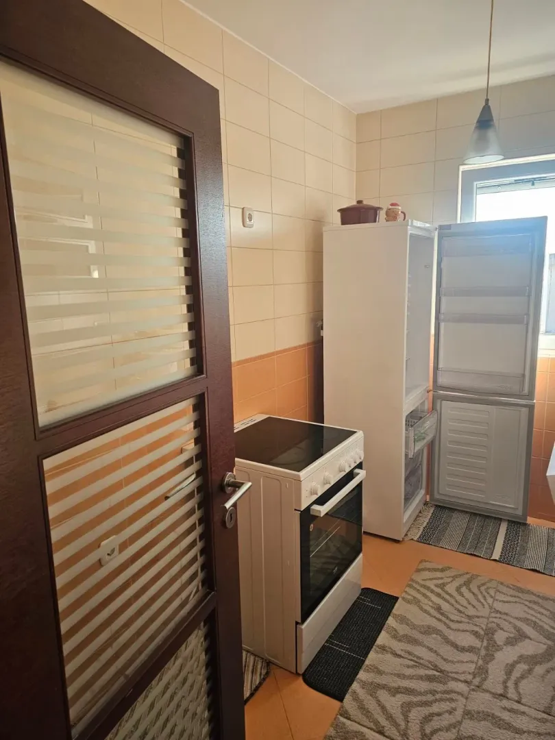 Smaller kitchen with a stove, refrigerator, and a door in the foreground.