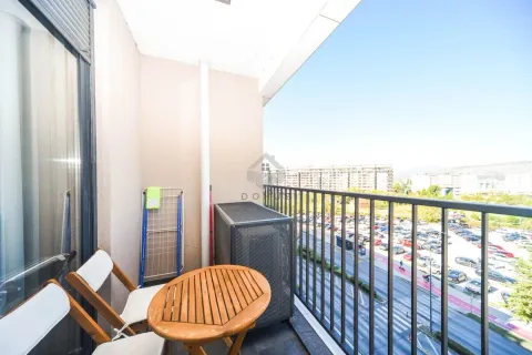 Manji natkriveni balkon sa drvenim stolom i stolicama i pogledom na ulicu. - image 11