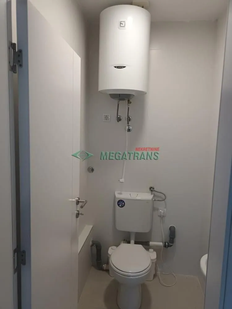 Small bathroom with a toilet and a water heater on the wall.