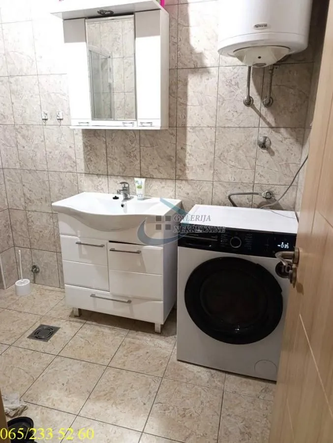 Kupatilo opremljeno umivaonikom, ogledalom, bojlerom i veš-mašinom.