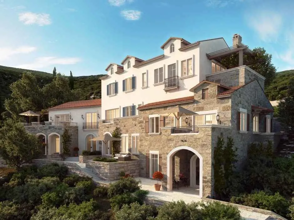 Pogled na spoljašnjost tradicionalne kamene kuće sa uređenim dvorištem i terasama.