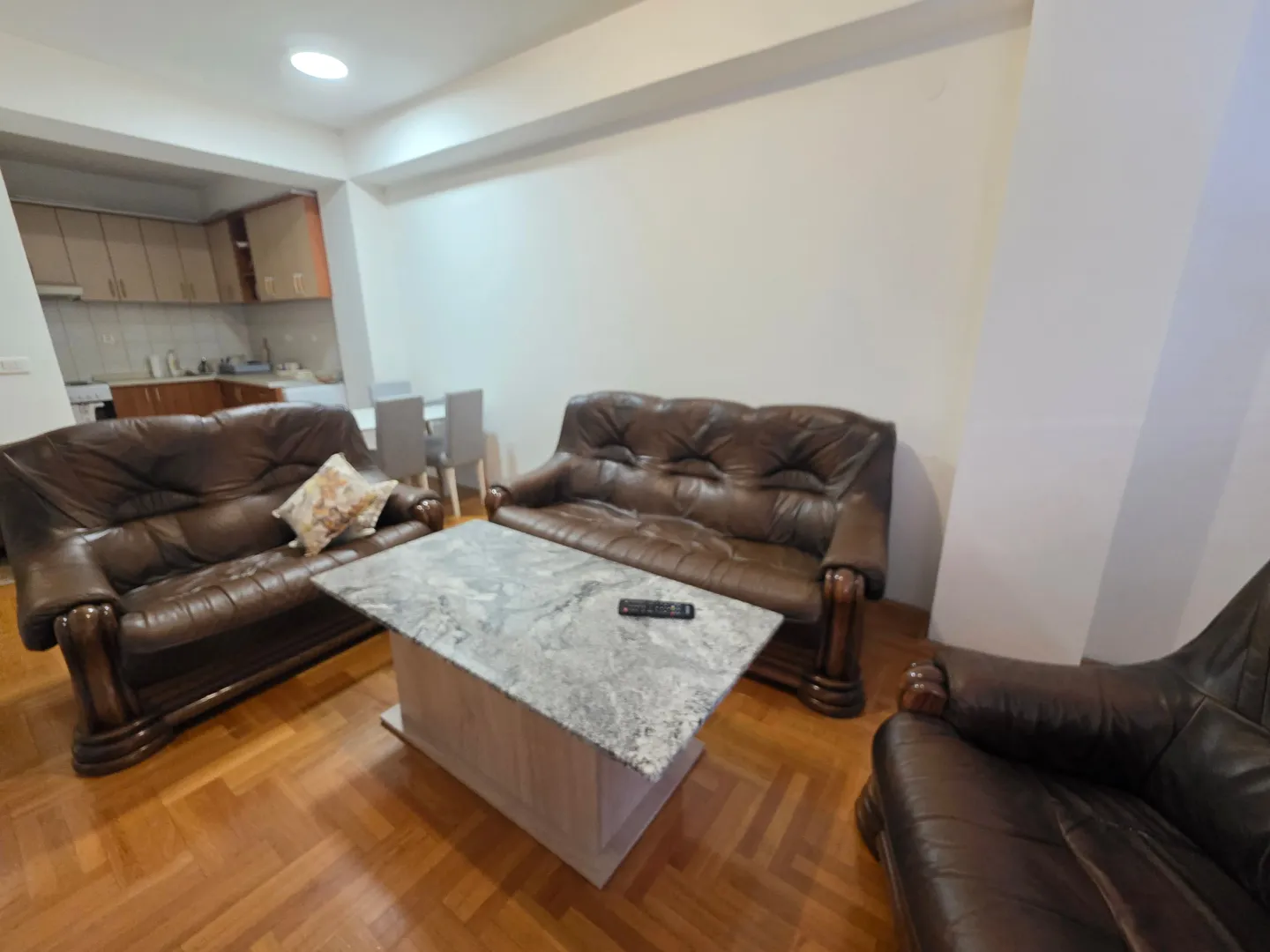 Spacious living room with seating set and table, connected to the kitchen.