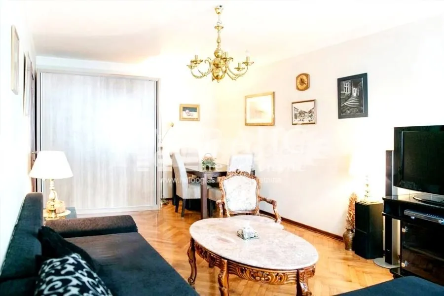 Furnished living room with sofa set, dining table, and television.
