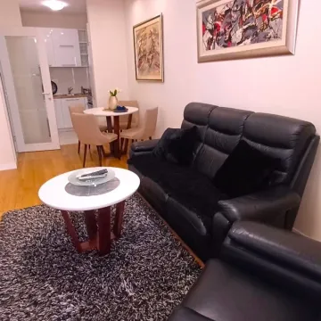 Dnevni boravak sa garniturom i stolom, sa pogledom na trpezariju i kuhinju u pozadini. - image 3