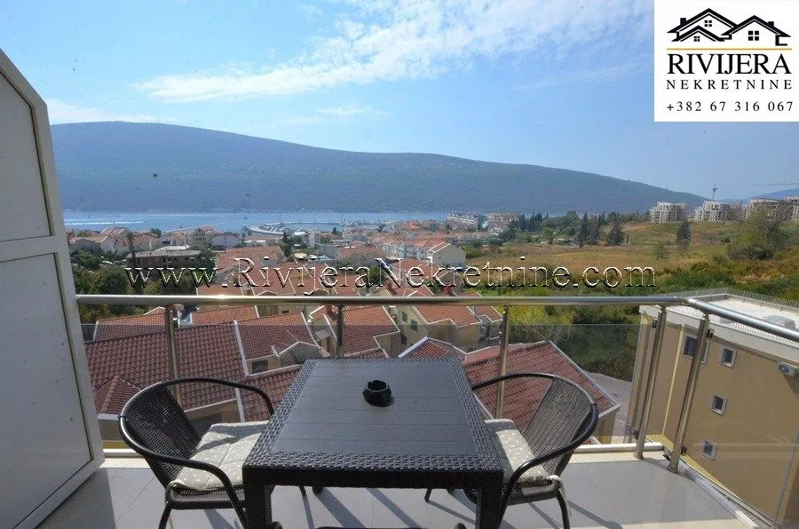 Namješten balkon sa stolom i stolicama i pogledom na more.