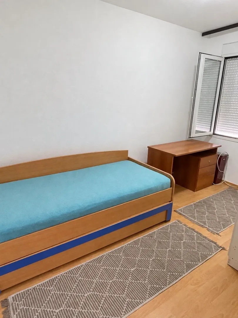 Children's bedroom with a bed, desk, and window.