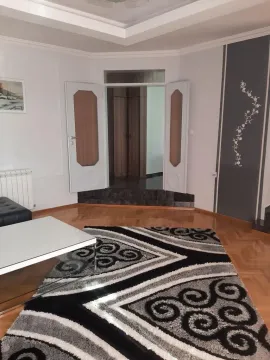 Living room with parquet flooring, a rug, and double doors. - image 13
