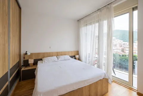 Svijetla spavaća soba sa bračnim krevetom, drvenim plakarom i izlazom na terasu. - image 6