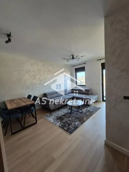 Living room with a sofa, dining area, and hardwood flooring.