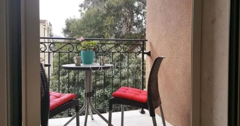 Manji namješten balkon sa stolom, stolicama i pogledom na zelenilo.
