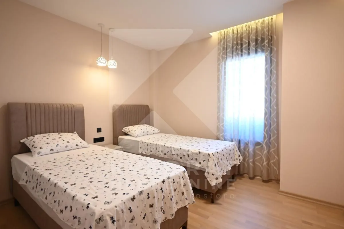 Bedroom with two single beds and a window with curtains.