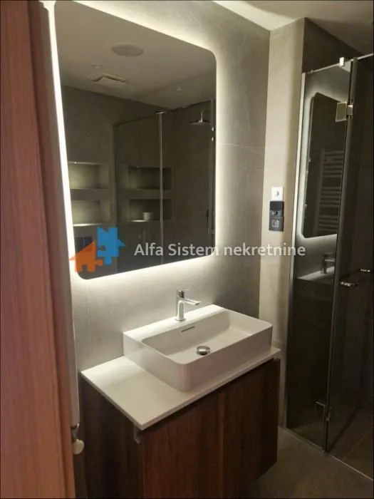 Modernly equipped bathroom with a washbasin and a large backlit mirror.