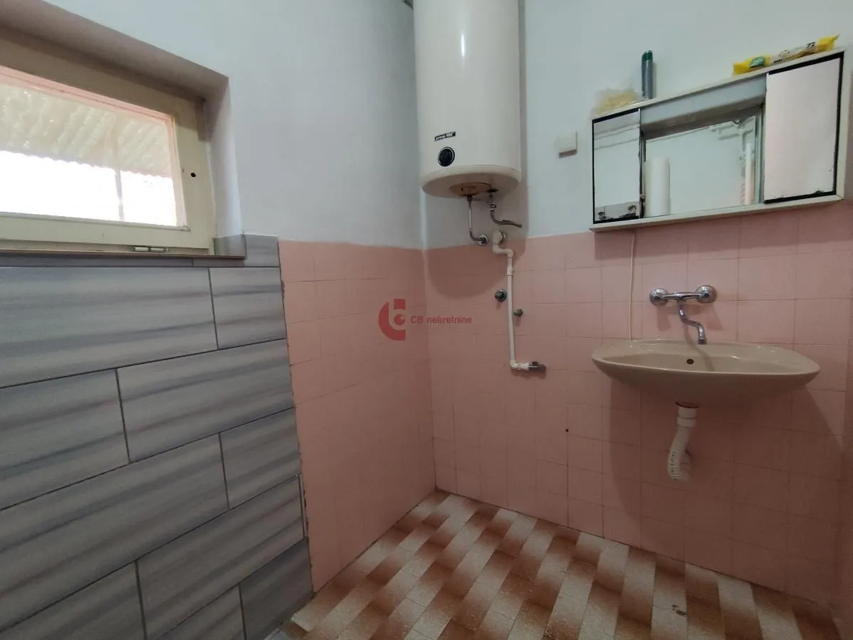 Manje kupatilo sa lavaboom, bojlerom i pločicama.