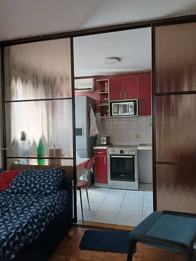 View from the room into a smaller kitchen with red cabinets.