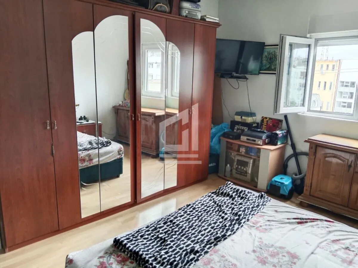 Namještena spavaća soba sa velikim drvenim ormarom sa ogledalima i krevetom.