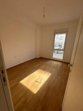 Prazna soba sa drvenim parketom i prozorom. - image 2