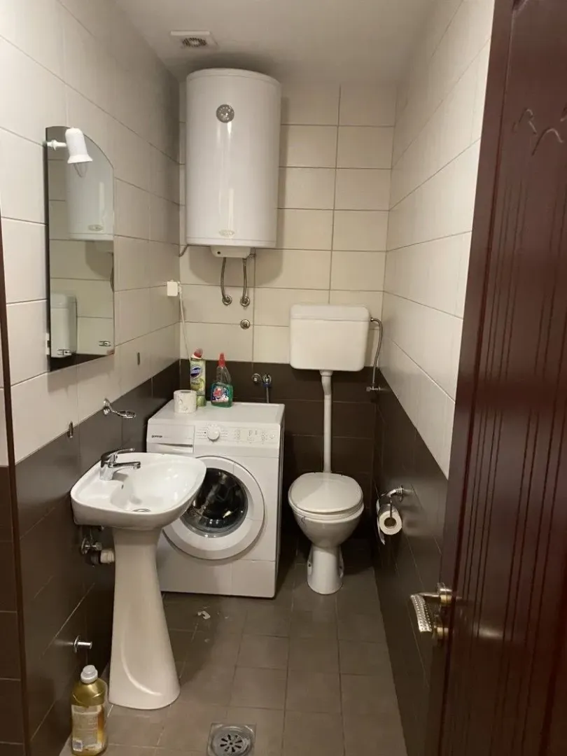 Manje kupatilo sa umivaonikom, WC šoljom, bojlerom i veš mašinom.