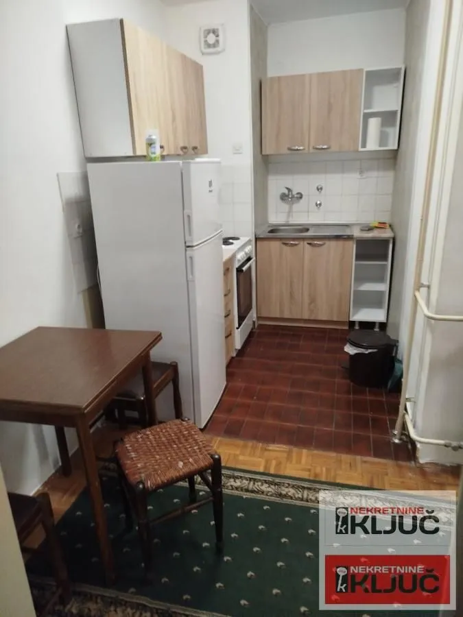 Manja kuhinja sa trpezarijskim stolom i frižiderom.
