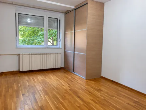 Prazna spavaća soba sa ugradnim ormarom, drvenim parketom i prozorom. - image 7