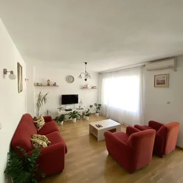 Prostrani dnevni boravak sa crvenim garniturama i drvenim podom. - image 4
