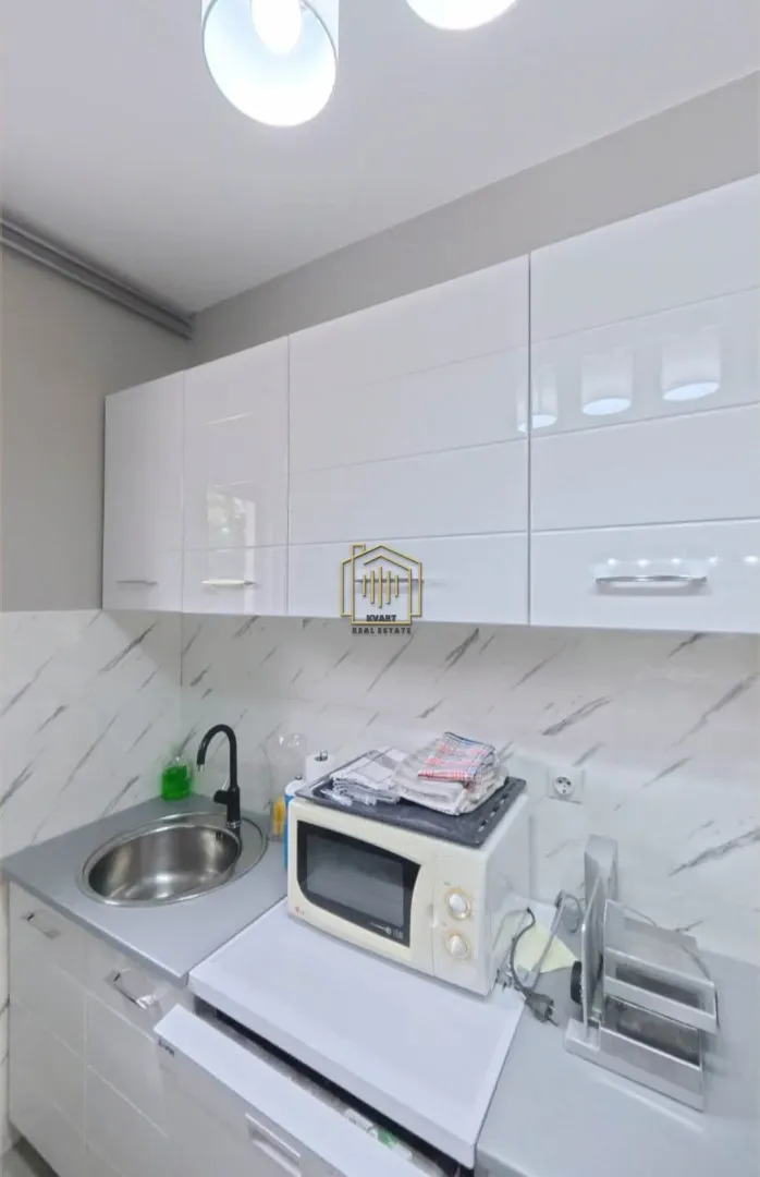 Small kitchen with white cabinets, a sink, and a microwave.