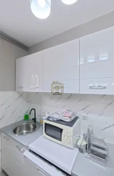 Small kitchen with white cabinets, a sink, and a microwave. - image 5