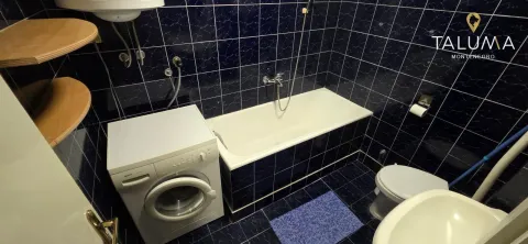 Kupatilo obloženo tamnoplavim pločicama sa kadom, veš mašinom i sanitarijama. - image 8