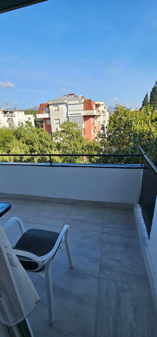 Namješten balkon sa pogledom na okolne zgrade i zelenilo.