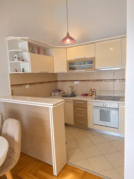 Smaller kitchen in beige tones with a built-in oven and a breakfast bar. - image 3