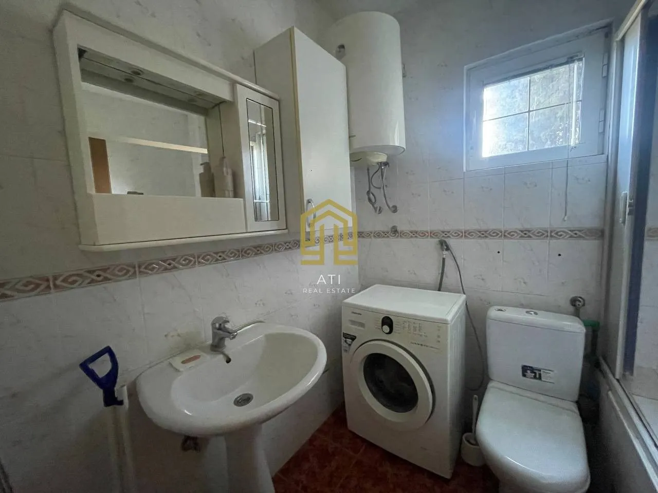 Smaller equipped bathroom with a sink, washing machine, and toilet.