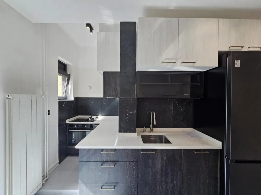 Modern kitchen with dark cabinetry and white countertops.