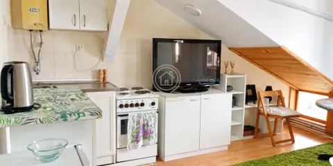 Manja kuhinja u potkrovlju sa šporetom, frižiderom i televizorom na komodi. - image 3