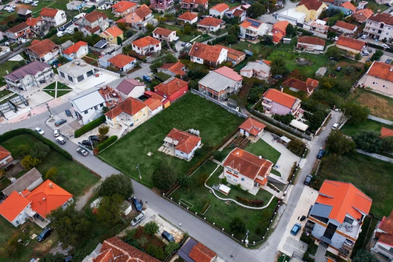 Pogled iz vazduha na prigradsko naselje sa porodičnim kućama i dvorištima.