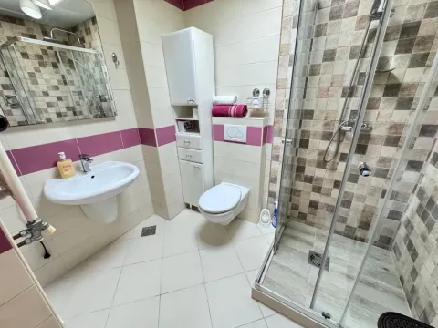 Tidy bathroom with a shower cabin, sink, and toilet. - image 6