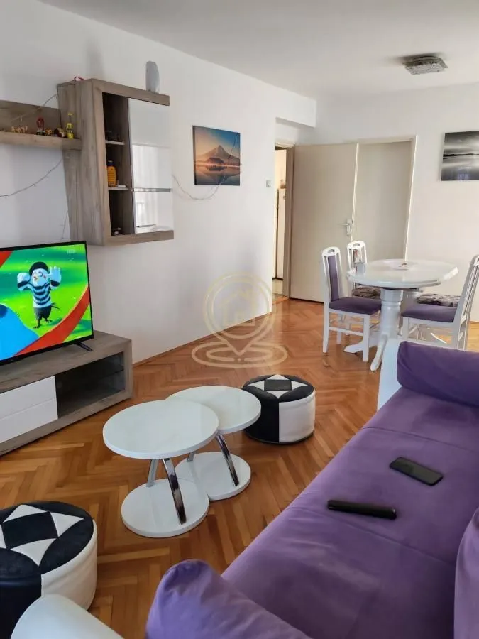 Living room with sofa, TV and dining table in the background.