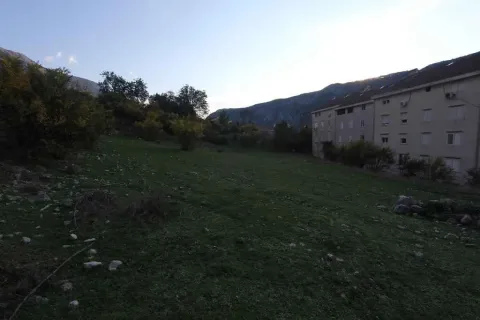 Travnata parcela pored stambene zgrade sa brdima u pozadini. - image 4