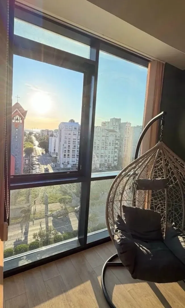 Dnevna soba sa velikim prozorom i visećom foteljom.