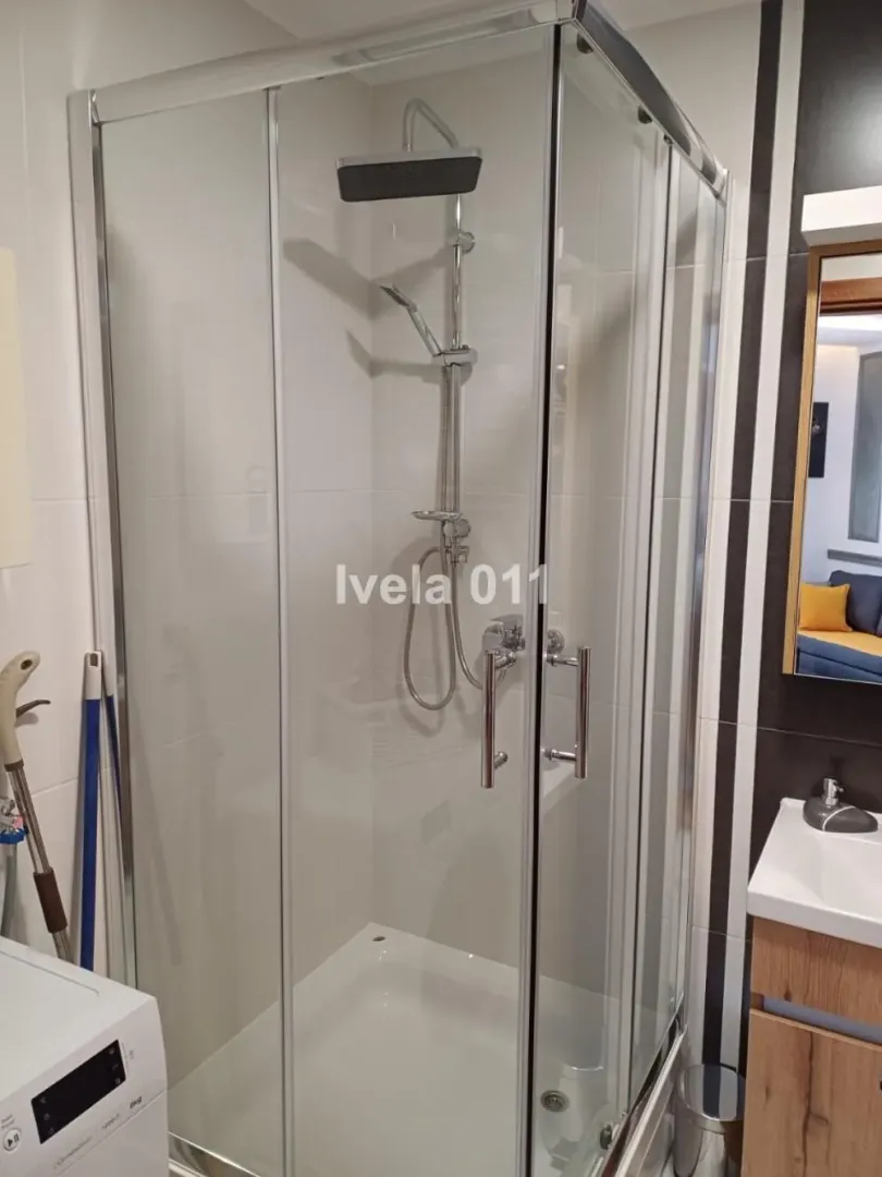 Bathroom with a shower cabin, washbasin, and washing machine.