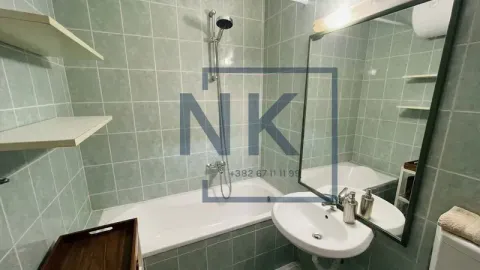 Bathroom equipped with a bathtub, washbasin, mirror, and wall tiles. - image 4