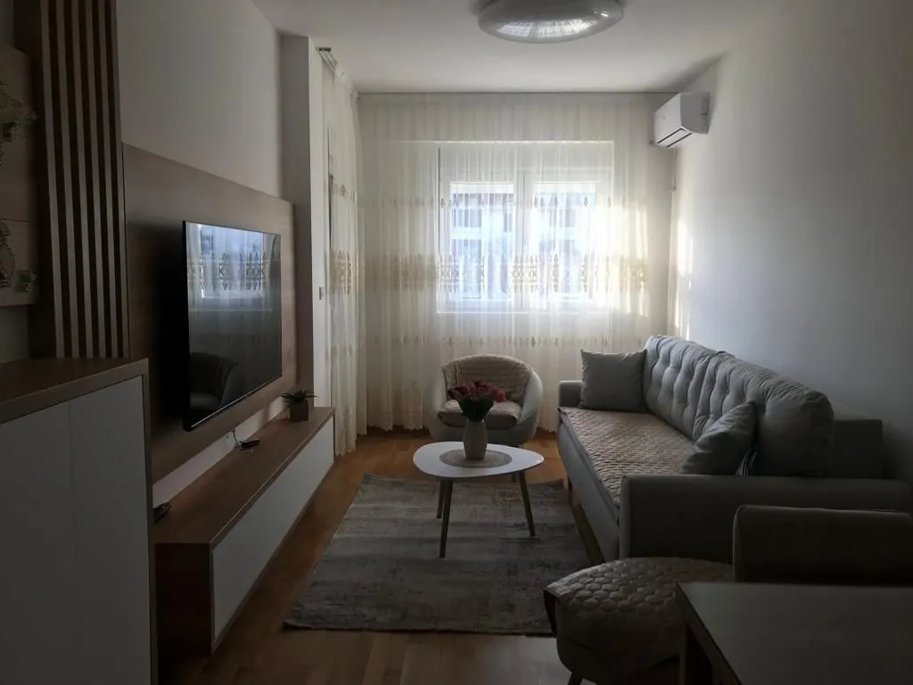 Bright living room with a grey sofa and mounted TV.