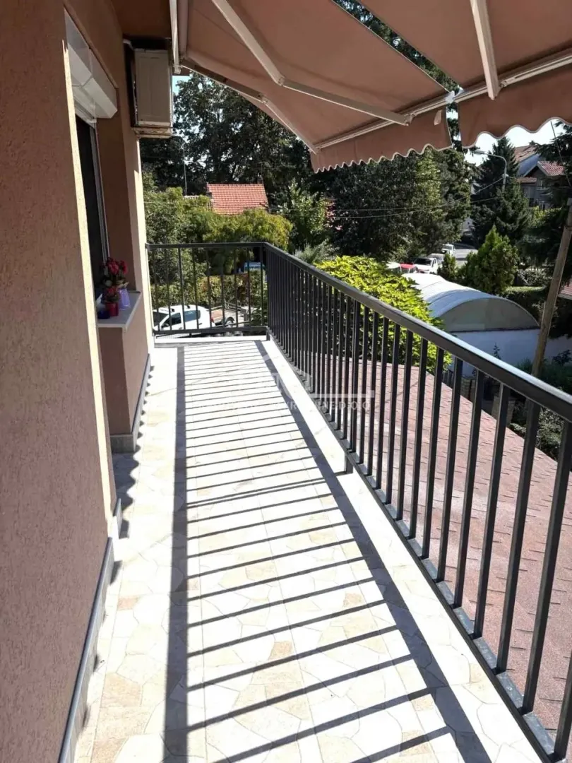 Spacious balcony with a metal railing and a sun awning providing shade.