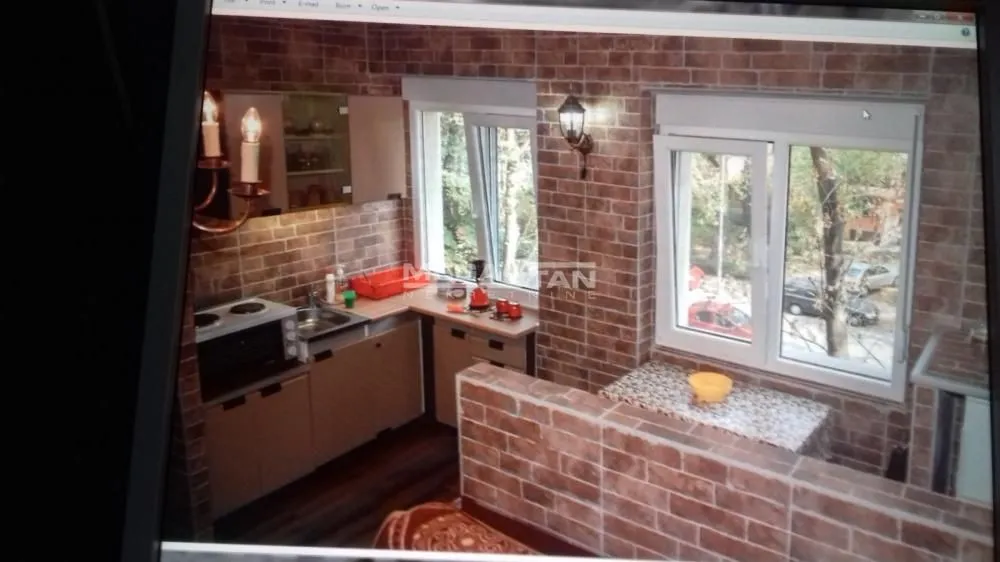 Smaller kitchen with brick-clad walls and a window overlooking the outside.