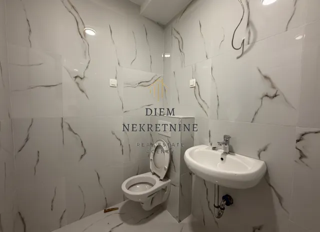 Small bathroom tiled with marble-pattern ceramic tiles.