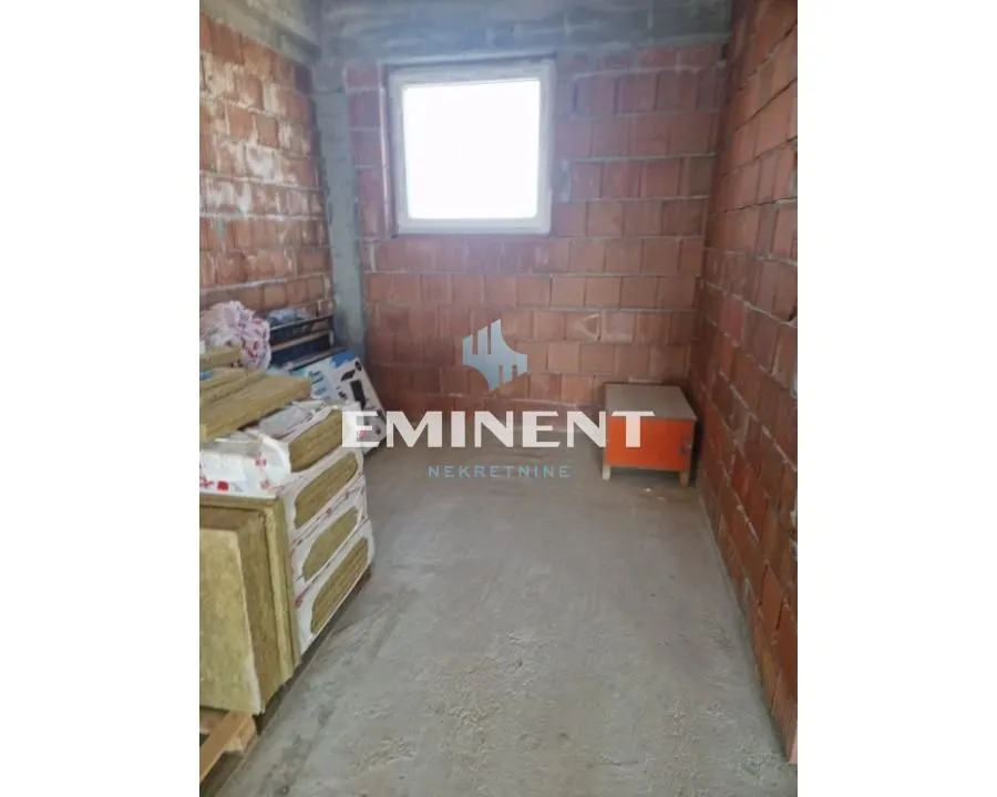 Unfinished room with brick walls and a window under construction.