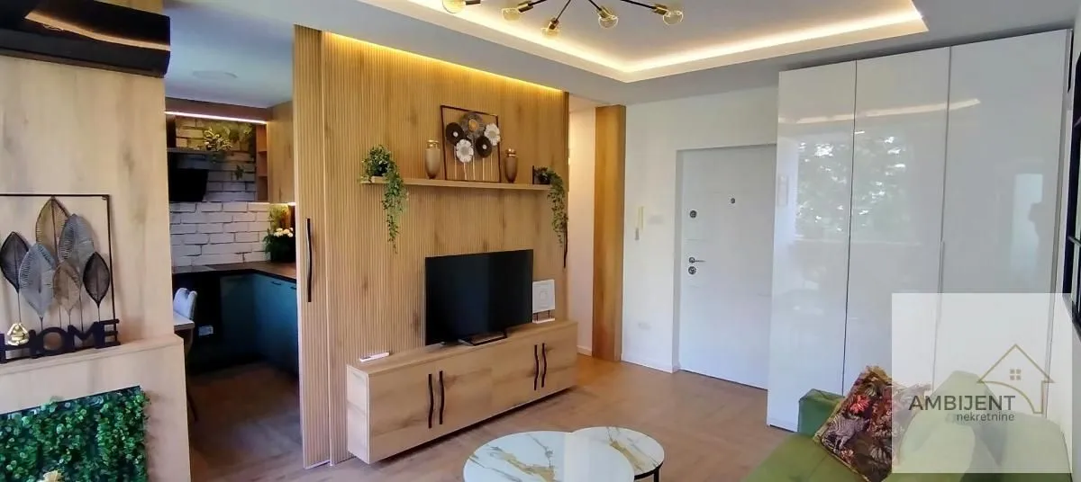 Living room with wooden wall panels and TV unit.
