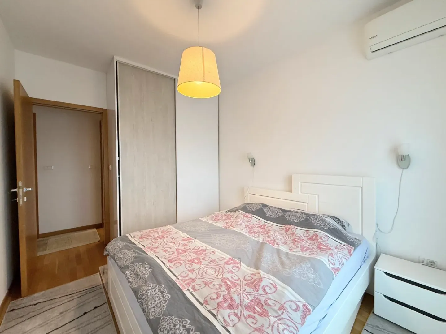 Bright and tidy bedroom with a double bed, built-in wardrobe, and air conditioning.