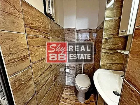 Small bathroom tiled in brown with a toilet and washbasin. - image 18