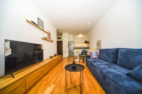Living room with a blue sofa, wooden TV cabinet, and a view of the kitchen. - image 11